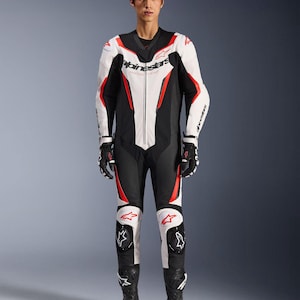 May include: A black, white, and red motorcycle racing suit. The suit features a black collar, white torso with red accents, black legs, and white knee pads. The suit has the "Alpinestars" logo on the chest and sleeves.