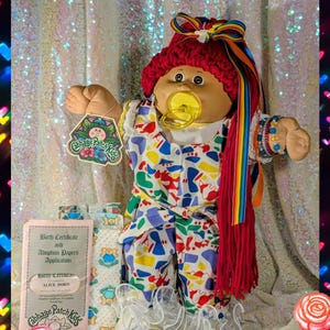 May include: A white ceramic mug with a black handle and the text "But First, Coffee" in a bold, black font. The mug is set against a blurred background, suggesting a cozy setting.