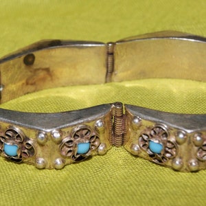 May include: Silver bracelet with a hinged clasp and turquoise stones set in filigree designs.