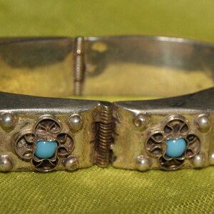 May include: Silver hinged bangle bracelet with a decorative design and turquoise blue stones.