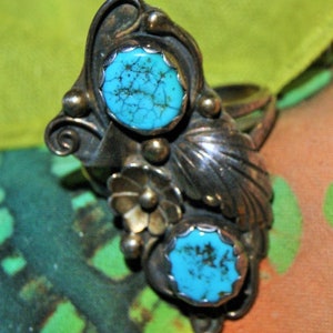 May include: A silver ring with two turquoise stones set in a leaf design.