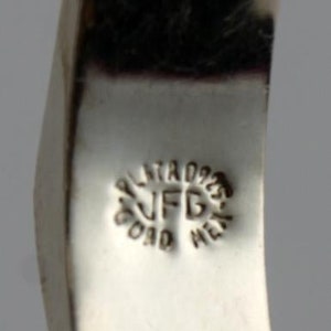 May include: Close-up of a silver bracelet with a textured design. The bracelet has a stamp that reads "Plata 925 JFD Oro Metal".