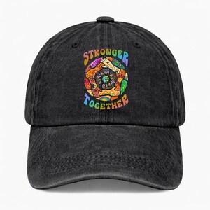 May include: Black denim baseball cap with a colorful graphic. The graphic features a circle of hands and the words "STRONGER TOGETHER" in rainbow colors. The cap has a curved brim and an adjustable strap.