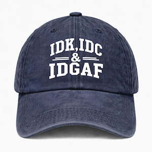 May include: A navy blue baseball cap with a distressed, washed-out texture. The front features white, block-style lettering that reads IDK, IDC & IDGAF arranged in three lines with horizontal lines flanking the ampersand in the center.