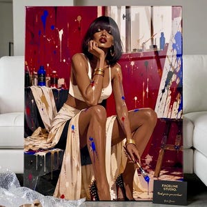 May include: A glossy art print featuring a person with dark hair and red lips wearing a cream-colored top and skirt, sitting in a studio with red walls splattered with blue, white, and gold paint. The person holds a paintbrush with blue paint.