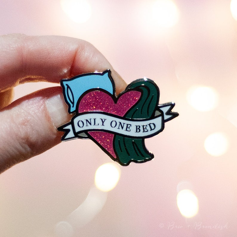 May include: A pink glitter heart with a blue pillow and green wave design. The heart has a white banner with the text "ONLY ONE BED".