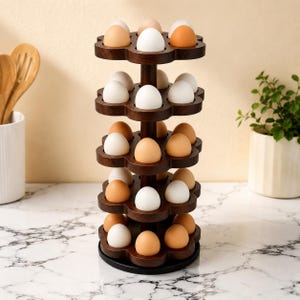 May include: A vertical, multi-tiered dark wood egg holder featuring a rotating design with scalloped circular shelves. The stand holds numerous white and brown eggs in individual carved indentations, arranged in a stacked, space-saving structure.