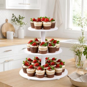 May include: A three-tiered white cupcake stand holding numerous cupcakes topped with fresh strawberries. Each cupcake is in a brown paper liner, featuring a light-colored cake base, a layer of white frosting, and a single whole red strawberry.