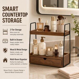 May include: A two-tier countertop storage organizer featuring a dark wood finish and a black metal frame. The unit includes an open top shelf and a bottom shelf with a built-in drawer. Various skincare bottles, jars, and makeup brushes are displayed.