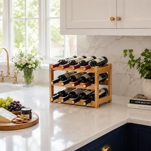 May include: A three-tier bamboo wine rack holding nine wine bottles with dark glass and cork stoppers. The rack features a natural light wood finish and a rectangular frame, designed to store bottles horizontally in a kitchen setting.