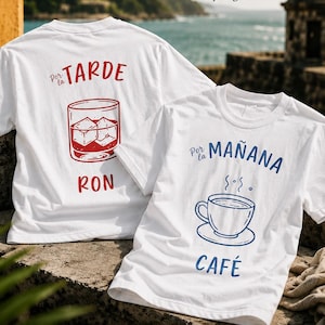 May include: Two white t-shirts featuring graphic prints. One shirt displays a red illustration of a glass with ice and the text Por la TARDE RON. The other shirt shows a blue illustration of a coffee cup and the text Por la MAÑANA CAFÉ.
