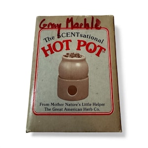 May include: A vintage box for "The SCENTsational HOT POT" from The Great American Herb Co. The box features a drawing of a small, tan pot with a round opening. The text "Gray Machle" is written at the top.