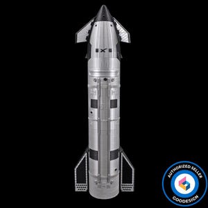 May include: A silver and black model of a Starship rocket featuring a pointed nose cone, two upper flaps, and two lower fins. The cylindrical body displays a metallic texture with vertical panel lines and a black X logo near the top section.