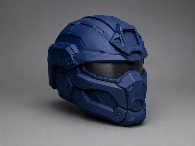 May include: A matte navy blue tactical helmet featuring a multi-paneled geometric design, a dark tinted visor, and a reinforced front faceplate with integrated ventilation details. The helmet has a structured shell with raised ridges and grooves.