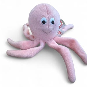 Peut inclure: Une peluche rose en forme de poulpe avec huit tentacules. Le poulpe a de grands yeux ronds et un visage souriant. Une petite étiquette est attachée à l'un des tentacules. Le jouet est conçu pour les enfants.