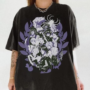 Pu&ograve; includere: T-shirt nero con una grafica di personaggi anime in bianco, nero e grigio, circondati da forme di foglie viola. Un simbolo a forma di ragno &egrave; in cima al design. La maglietta ha un aspetto vintage e sbiadito.