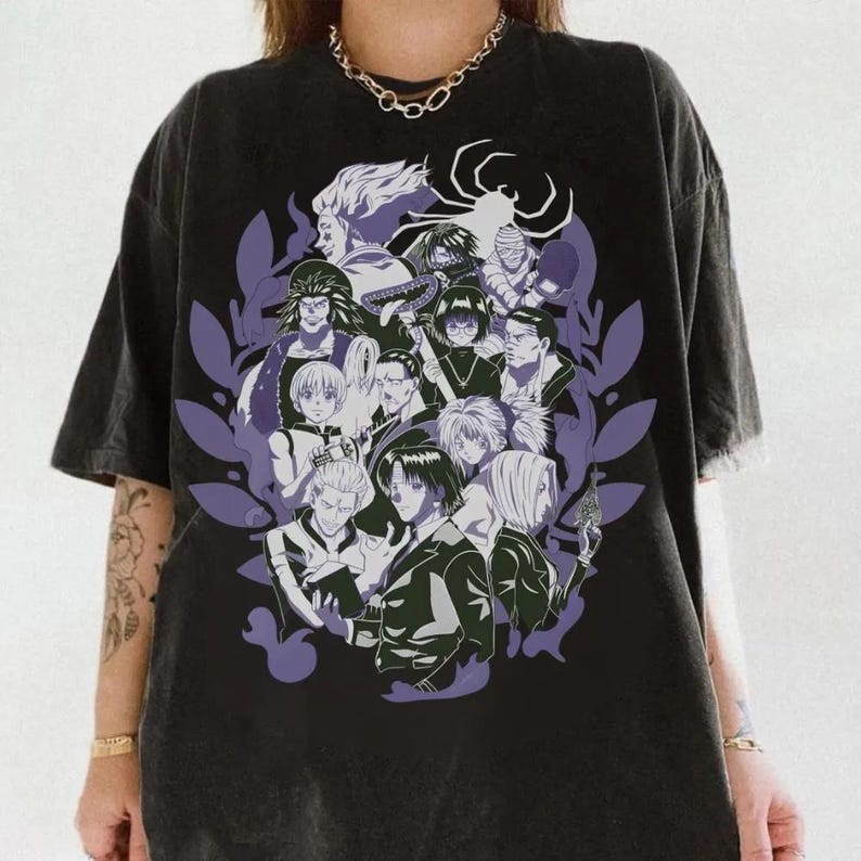 Pu&ograve; includere: T-shirt nero con una grafica di personaggi anime in bianco, nero e grigio, circondati da forme di foglie viola. Un simbolo a forma di ragno &egrave; in cima al design. La maglietta ha un aspetto vintage e sbiadito.