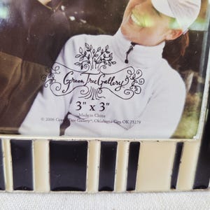 May include: A decorative photo frame with a black, white, and cream-colored striped border. The frame is designed to hold a 3-inch by 3-inch photo. The text "Green Tree Gallery" is visible, along with the dimensions and manufacturing information.