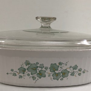 May include: White oval baking dish with a glass lid. The dish has a green floral design with vines and leaves.