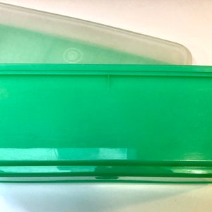 Peut inclure: Un récipient de rangement en plastique vert avec un couvercle transparent. Le récipient est rectangulaire et a une surface lisse.