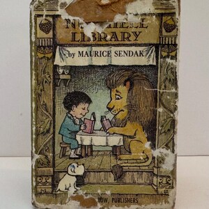 May include: A vintage book cover with a green background featuring a boy and a lion reading books at a table. The text on the cover reads "The Little Library by Maurice Sendak".