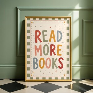Könnte beinhalten: Ein gerahmter Kunstdruck mit dem Text READ MORE BOOKS in mehrfarbiger, handgezeichneter Schrift. Das Design umfasst einen karierten Rand in gedecktem Grün und Creme, akzentuiert durch kleine Sternformen auf cremefarbenem Hintergrund.
