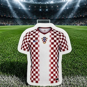 Pu&ograve; includere: Una maglia da calcio a maniche corte con un motivo a scacchi rossi e bianchi sulle maniche e sui lati, e un pannello verticale bianco solido al centro. La maglia presenta un logo blu scuro sul petto destro e uno stemma della squadra al centro.