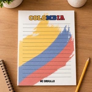 May include: A white notepad sheet featuring the word COLOMBIA at the top and MI ORGULLO at the bottom. The center displays a brushstroke design in yellow, blue, and red, mimicking the Colombian flag, overlaid with thin horizontal black lines.