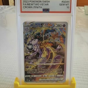 Puede incluir: Una taza de cer&aacute;mica blanca con un asa negra y el texto "But First, Coffee" en negrita negra. La taza est&aacute; sobre una superficie de madera. La taza mide 10 cm de alto.