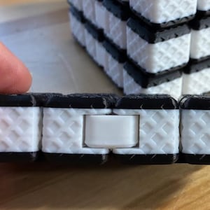 Può includere: Una tazza di ceramica bianca con manico nero e la scritta "But First, Coffee" in grassetto nero. La tazza è posta su uno sfondo sfocato, che suggerisce un'ambientazione accogliente. La tazza è alta circa 10 cm.