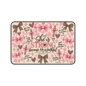 May include: A rectangular mat featuring a light background with pink bows, leopard print hearts, and brown crosses. The text reads: She is STRONG because He is faithful, along with various Bible verses and inspirational phrases.