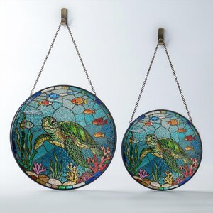 May include: Two round stained glass panels depicting a sea turtle swimming among colorful fish and coral. The panels are in shades of blue, green, red, and orange, and are suspended by metal chains.