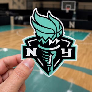 May include: A die-cut sticker featuring a stylized graphic of a basketball held like a torch, colored in mint green, black, and white. The design includes a hand gripping the torch handle and the letters N and Y on either side of the central emblem.