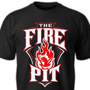 May include: A black short-sleeved t-shirt featuring a graphic design on the chest. The design displays the text THE FIRE PIT in bold white letters with red outlines, centered above and below a stylized illustration of a bright red and white flame.