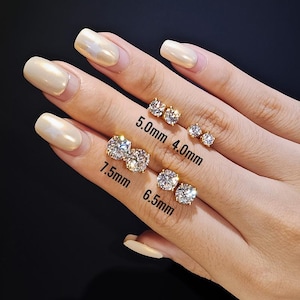 May include: A hand displays several pairs of gold-colored stud earrings with clear, round gemstones. Sizes are labeled as 4.0mm, 5.0mm, 6.5mm, and 7.5mm. The earrings are set against a dark background.