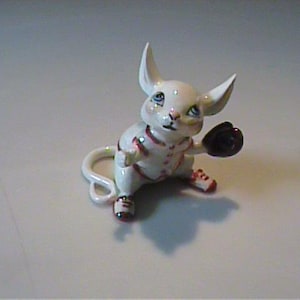 May include: A white ceramic mug with a black handle and the text "But First, Coffee" in a bold, black font. The mug is set against a blurred background, suggesting a cozy setting.