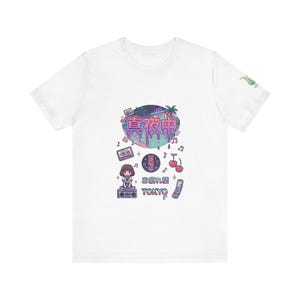 May include: White t-shirt with a vibrant graphic design incorporating Japanese text and illustrations. The design includes a cityscape, musical notes, cherries, and a retro aesthetic. The word "TOKYO" is also visible.