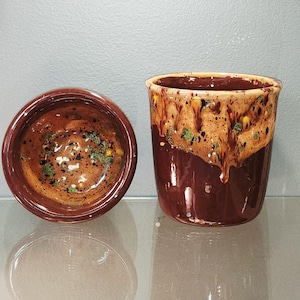 May include: A ceramic cup and a matching bowl featuring a glossy dark brown base glaze. The upper sections are decorated with a textured, drippy tan glaze overlay, accented by small, scattered dark brown and green speckles throughout the surface.