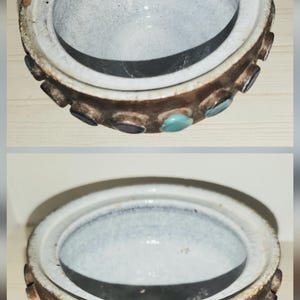 May include: A ceramic bowl with a white interior and a brown exterior. The rim is decorated with various colored circular accents. The bowl is round and has a lid. The bowl is likely handmade.