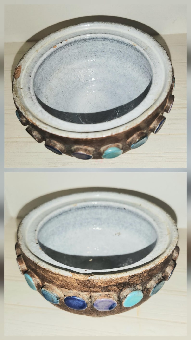 May include: A ceramic bowl with a white interior and a brown exterior. The rim is decorated with various colored circular accents. The bowl is round and has a lid. The bowl is likely handmade.