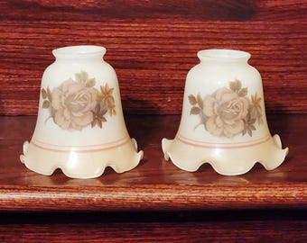 May include: Two vintage bell-shaped lamp shades. Each shade is off-white with a floral rose design in shades of brown and tan. The bottom edge has a scalloped design with a light peach color.