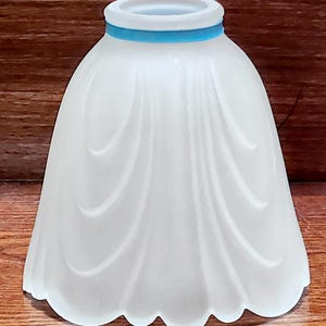 May include: White frosted glass lampshade with a scalloped edge and a blue trim around the top.
