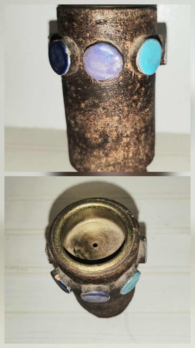 May include: A handcrafted, cylindrical ceramic vase with a textured, brown exterior. The vase is adorned with three colorful, circular accents: blue, purple, and turquoise. The top view reveals a circular opening and a small drainage hole.
