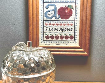 Vintage Sampler cross stitch, A is for Apple framed, 8 3/4" tall by 6 3/4" wide.  Dated 1995 signed by "BJ"