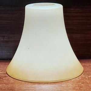May include: A bell-shaped glass lamp shade with a smooth, frosted finish. The shade features a gradient colour transition, starting with a pale cream tone at the narrow top opening and deepening into a warm, golden amber hue at the wide bottom rim.