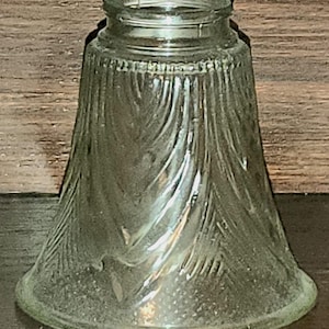 Op de afbeelding: Een glazen lampenkap van helder glas met een swirl-patroon. De kap is klokvormig en heeft een gladde, afgeronde bodem.