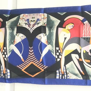 May include: A blue silk scarf with a geometric pattern featuring two figures in a stylized art deco design. The figures are outlined in black and have yellow, red, and white accents. The background is a mix of black, white, and blue.