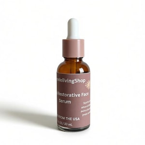 May include: A brown glass bottle of Restorative Face Serum with a white dropper and a mauve cap. The label reads "anlelivingShop" and "Restorative Face Serum". The bottle contains 1 fl oz / 30 mL of product.