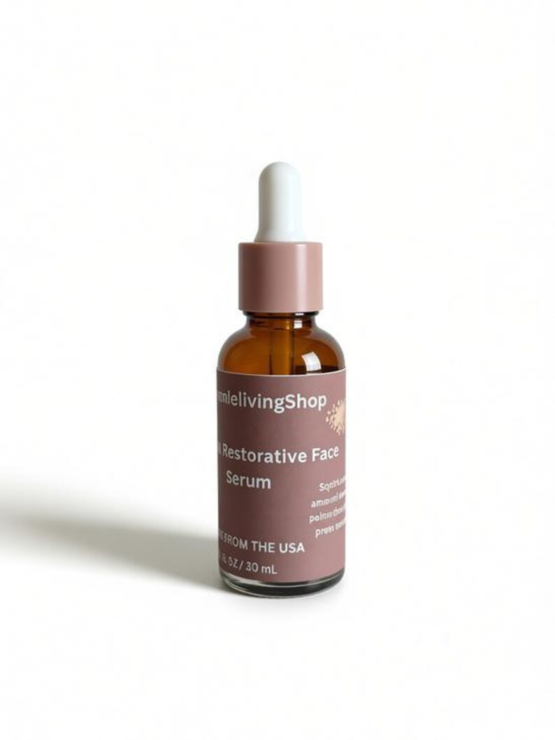 May include: A brown glass bottle of Restorative Face Serum with a white dropper and a mauve cap. The label reads "anlelivingShop" and "Restorative Face Serum". The bottle contains 1 fl oz / 30 mL of product.