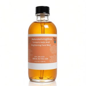 May include: A clear glass bottle filled with amber-coloured Turmeric Kojic Acid Brightening Face Wash. The label reads NaturalelivingShop, Turmeric Kojic Acid Brightening Face Wash, EXP JAN 2029, MADE IN THE USA, and 4 FL OZ / 118 mL. It has a black cap.